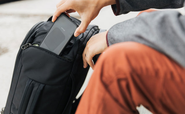 A person putting their phone into the Techonaut 30's smaller side pocket.